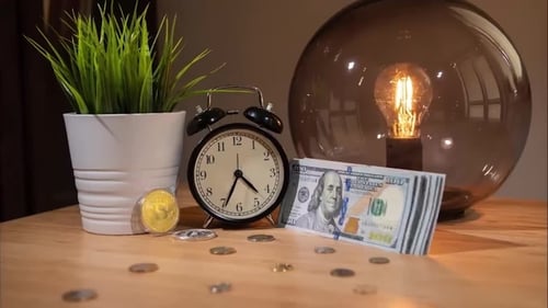 Bitcoin Fast Rising Price. View of Bitcoins, Alarm Clock and Small Bundle of Dollars on Table