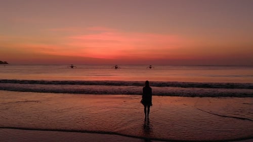 Woman Silhouette on Beach at Pink Sunrise