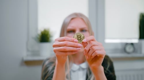 Woman Studying Bitcoin in Hands