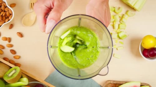 Hände einschalten Mixer mit geschnittenem grünem Gemüse in Nahaufnahme