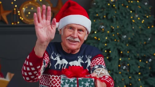 Senior Man Holding Christmas Gift and Wearing Santa Hat