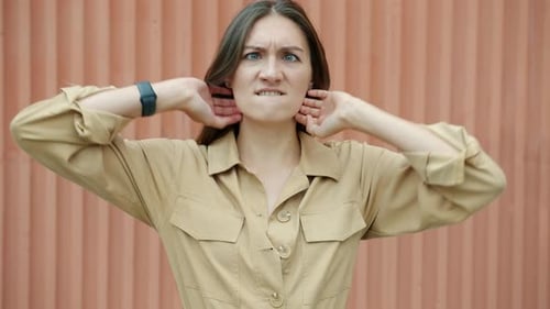 Zeitlupenporträt einer verspielten jungen Frau, die draußen lustige Grimassen mit Wand im Hintergrund macht