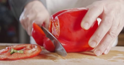 Slow motion close up of a chef knife slicing a Red bell pepper