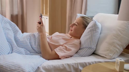 Woman Lies in Bed Using Mobile Phone