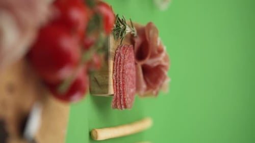 Vertical video, Close-up: cold cuts, salami, prosciutto, jamon, cherry tomatoes, sliced sausage