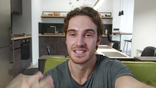 Smiling man talking to camera in modern apartment
