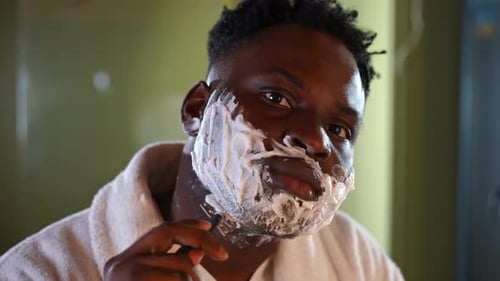 Foto da cabeça do homem concentrado barbear restolho com navalha olhando para a câmera