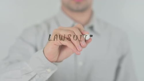 Hand Writes Lawsuits With Marker on Glass