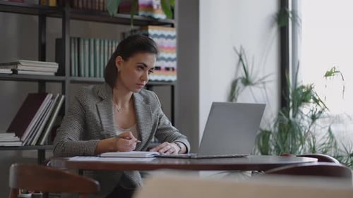 Woman Working From Home Using Laptop Computer While Reading Text Message