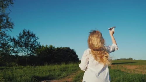 Girl Running with Paper Airplane in Rural Field