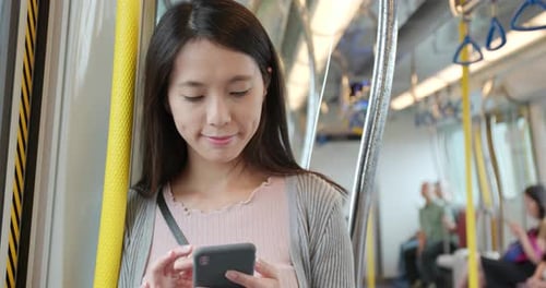 Woman Uses Smartphone on Subway Train