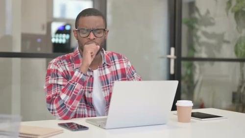 Young Adult Coughing While Working on Laptop