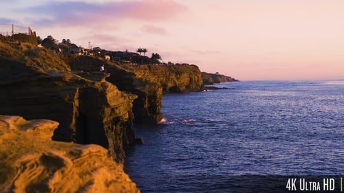 4K Woman Sitting on Rocky Sunset Cliffs Coastline in San Diego, California