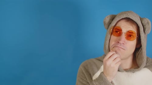Thoughtful Man Wearing Animal Onesie and Orange Glasses