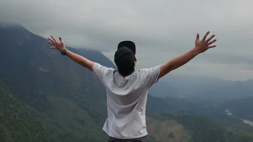 Man Standing on Mountain Top with Arms Raised