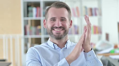 Porträt eines fröhlichen jungen Mannes klatschend applaudiert