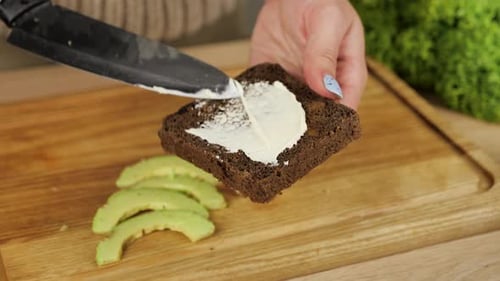 Making Cream Cheese Avocado Sandwich on Dark Bread