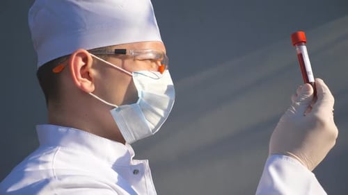 Doctor Exploring Test Tube with Blood Sample To Coronavirus. Medic with Protective Gloves and