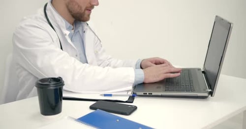 Männlicher Arzt arbeitet mit Laptop im Büro