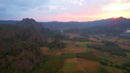 Aerial view a drone fly over a rural area with mountains in the background at sunrise.