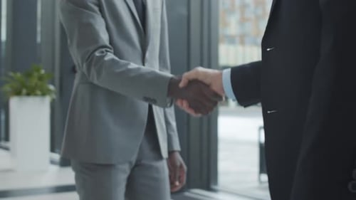 Nicht wiederzuerkennende multiethnische Geschäftsleute beim Händeschütteln im Büroflur