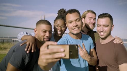 Lächelnde Freunde gestikulieren beim Selfie mit dem Smartphone