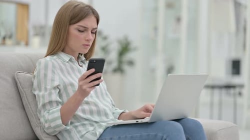 Woman Using Laptop and Mobile Phone on Couch