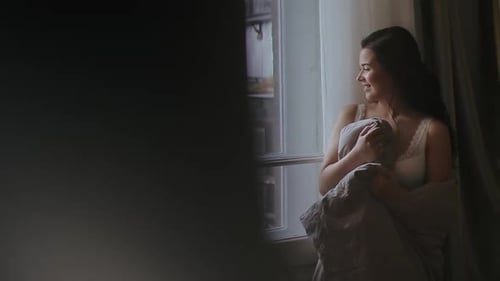 Beautiful Happy Woman Meets Warm Sunny Morning, Standing in the Bedroom By Window Door and Wrapped