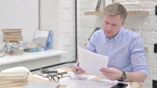Man Reviews Documents at His Office Desk