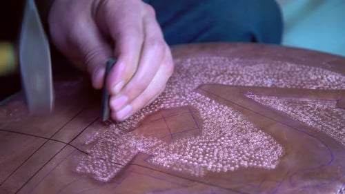 Craftsman Engraving Copper Metalwork with Chisel and Hammer