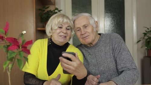 Senior Couple Using Smartphone Together Indoors