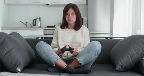 Woman Playing Video Game at Home on Sofa