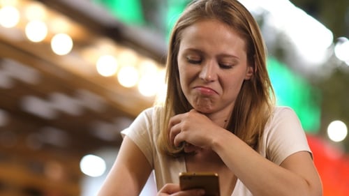 Distraught Woman Scrolling on Her Mobile Phone