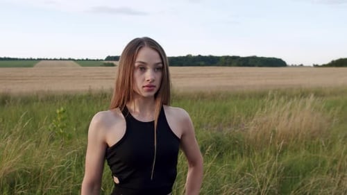 Woman Stands in Grassy Field on Rural Landscape