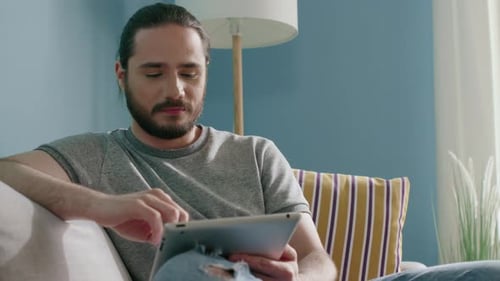 Young Adult Using Tablet Device at Home on Couch