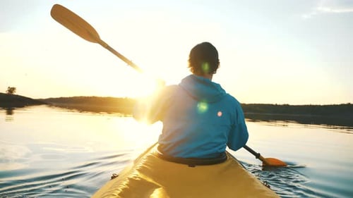 Outdoor Activities, Man Is Kayaking on Calm Lake Against Sunset Rays