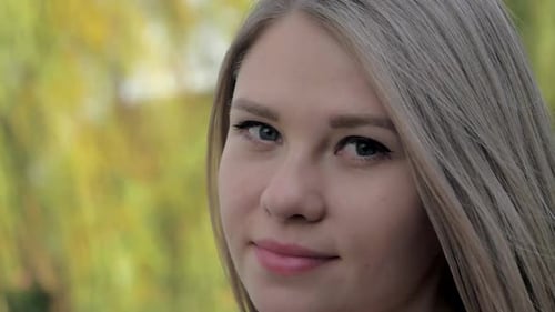 Portrait of a Beautiful Blonde Girl with Waving Hair Looking at Camera in the Park on Sunny Day