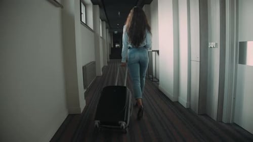 Young Woman Rolling Suitcase in Hotel Corridor. Slim Girl Crossing Hotel Space