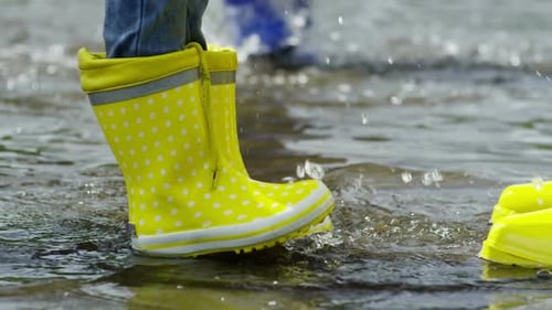 Child Splashing in Puddle Wearing Rain Boots