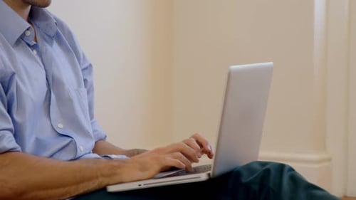 Man Working on Laptop Sitting on Floor Indoors