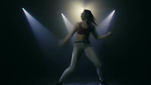 Woman Dancing Energetically Under Dramatic Studio Lighting