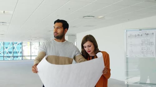 Business people discussing over blueprint in a modern office
