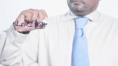 Adult Writes Leadership on Clear Surface