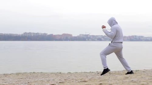 Individual Shadowboxing on Sandy Beach Near City