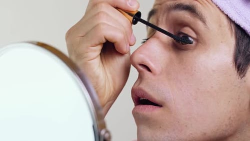 Young Adult Applies Mascara in Front of Mirror