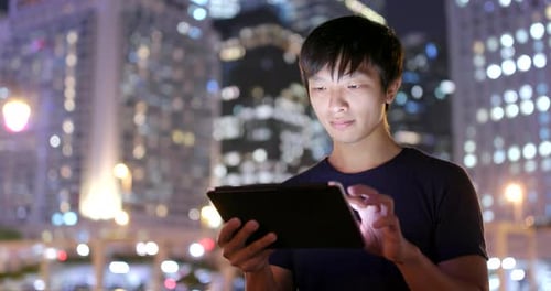 Young Adult Using a Tablet in the City at Night
