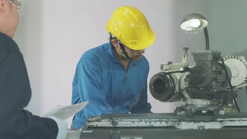 Asian mechanical technicians male workers working on milling machine in industrial factory.