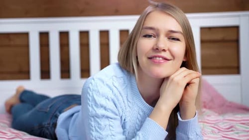 Woman Smiling, Lying Down on Bed in Bedroom