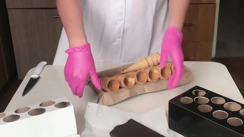 A Woman Arranges Waffle Cones And A Bar Of Chocolate On The Table.