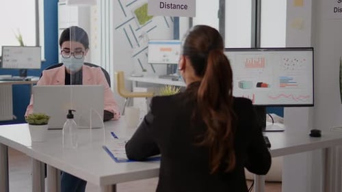 Un pigiste discute avec un collègue de la stratégie d'entreprise tout en étant assis dans un nouveau bureau normal